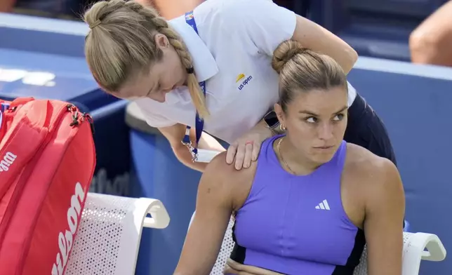 Maria Sakkari, of Greece, reacts as a trainer works on her shoulder between games against Wang Yafan, of China, during the first round of the U.S. Open tennis championships, Monday, Aug. 26, 2024, in New York. (AP Photo/Seth Wenig)