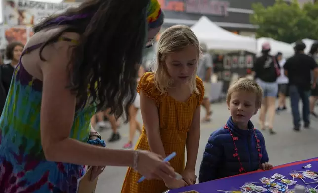 Illinois Rep. Kelly Cassidy, left, talks with visitors to the Glenwood Avenue Arts Festival, Quinn Kalman, 10, center, and Harrison Kalman, 6, left, Monday, Aug. 26, 2024, in Chicago. (AP Photo/Erin Hooley)