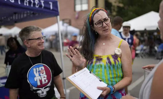 Illinois Rep. Kelly Cassidy, right, with her spouse, Candace Gingrich, left, talks with visitors to the Glenwood Avenue Arts Festival about canvassing efforts for the Democratic Party, Monday, Aug. 26, 2024, in Chicago. (AP Photo/Erin Hooley)