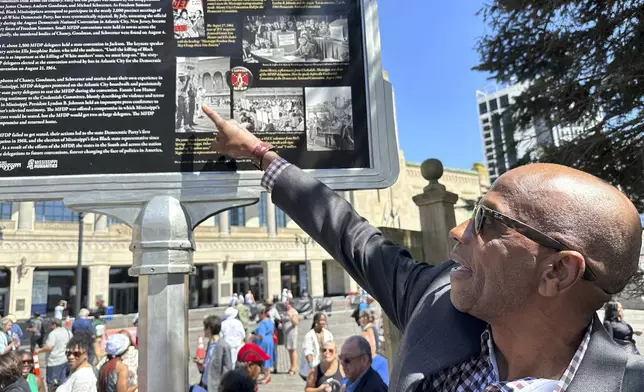 Roy DeBerry of the Student Nonviolent Coordinating Committee points to a photo of himself as a teenager on the newly unveiled Mississippi Freedom Trail marker on the boardwalk in Atlantic City, N.J., Tuesday, August 20, 2024. DeBerry was part of a racially-integrated group protesting the seating of an all-white Mississippi delegation to the 1964 Democratic National Convention at the location. (AP Photo/Ted Shaffrey)