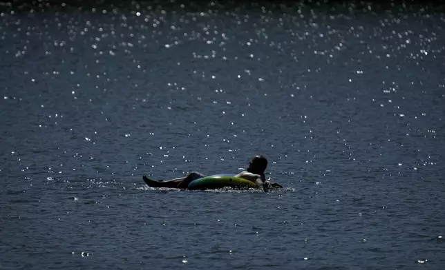 A tuber floats in the lake at Gray's Lake Park as the heat index tops 100 degrees, Monday, Aug. 26, 2024, in Des Moines, Iowa. (AP Photo/Charlie Neibergall)