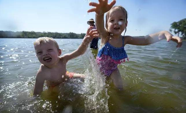 Judah, left, and Abby Boyle, of Des Moines, Iowa, splash in the water at the beach at Gray's Lake Park, Monday, Aug. 26, 2024, in Des Moines, Iowa. (AP Photo/Charlie Neibergall)