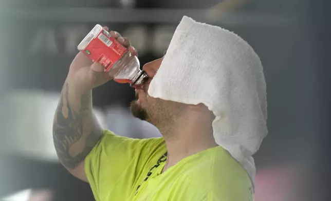 A construction worker hydrates at the Shedd Aquarium Tuesday, Aug. 27, 2024, as a second straight day of hot soupy temperatures approaching triple digits hung over much of the Midwest in Chicago. (AP Photo/Charles Rex Arbogast)