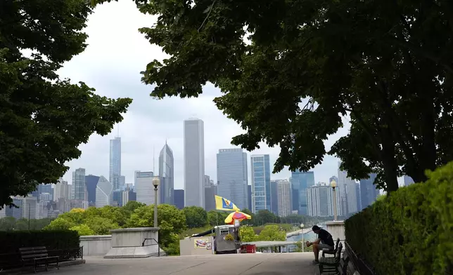 A man sits under the shade of a between the Field Museum and She'd Aquarium on Tuesday, Aug. 27, 2024, as a second straight day of hot soupy temperatures approaching triple digits hung over much of the Midwest in Chicago. (AP Photo/Charles Rex Arbogast)