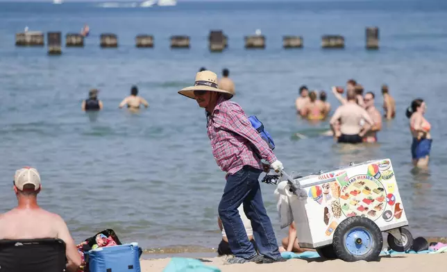 Gonzalo Garcia walks on North Avenue Beach selling ice cream on Monday, Aug. 26, 2024, in Chicago. (Eileen T. Meslar/Chicago Tribune via AP)