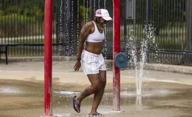 Samara Balans, 41, of Bronzeville, cools off in the water feature at River Park on the Northwest Side as temperatures across Chicago hit a high of 97 degrees, Tuesday, Aug. 27, 2024. (Ashlee Rezin/Chicago Sun-Times via AP)