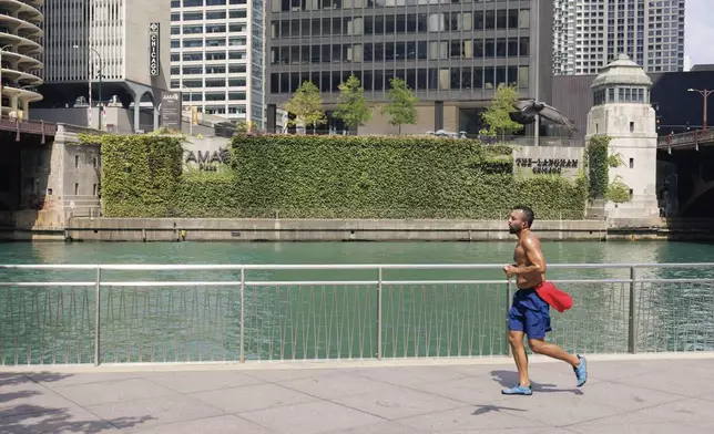 A jogger runs along the riverwalk in the loop, Tuesday, Aug. 27, 2024, as temperatures reached a high in the upper 90's. (Anthony Vazquez/Chicago Sun-Times via AP)