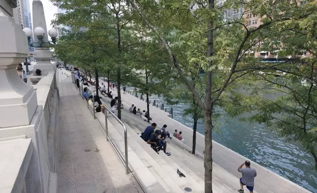 People sit along the riverwalk in the loop, Tuesday, Aug. 27, 2024, in Chicago, as temperatures reached a high in the upper 90's. (Anthony Vazquez/Chicago Sun-Times via AP)