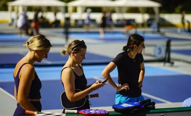 Women wait for friends to practice pickleball on the courts of CityPickle at Central Park's Wollman Rink, Saturday, Aug. 24, 2024, in New York. (AP Photo/Eduardo Munoz Alvarez)