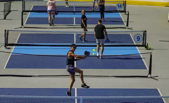 A man jumps to return the ball as people practice pickleball on the courts of CityPickle at Central Park's Wollman Rink, Saturday, Aug. 24, 2024, in New York. (AP Photo/Eduardo Munoz Alvarez)