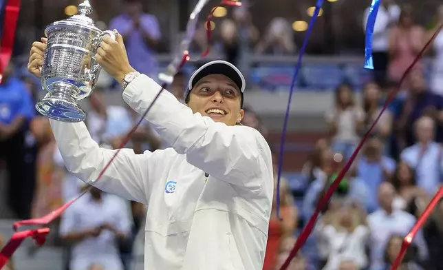 FILE - Iga Swiatek, of Poland, holds up the championship trophy after defeating Ons Jabeur, of Tunisia, to win the women's singles final of the U.S. Open tennis championships, Saturday, Sept. 10, 2022, in New York. (AP Photo/Frank Franklin II, File)