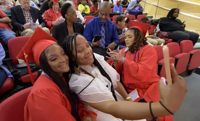 Gradute Chamaine Brown, left, poses with friend Christolyn Wilson, next to Danielle McGinnis, Brown's mother and also a graduate, before a high school equivalency (HiSET) diploma graduation ceremony for the Youth Empowerment Project (YEP) in New Orleans, Thursday, June 27, 2024. (AP Photo/Matthew Hinton)