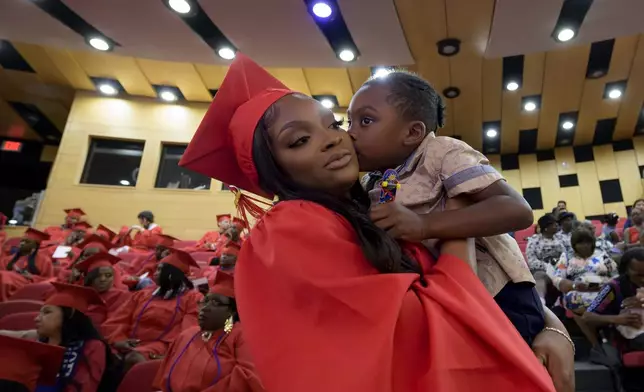 Chamaine Brown holds her son, Kelzie Lewis, 3, before a high school equivalency (HiSET) diploma graduation ceremony for the Youth Empowerment Project (YEP) in New Orleans, Thursday, June 27, 2024. (AP Photo/Matthew Hinton)