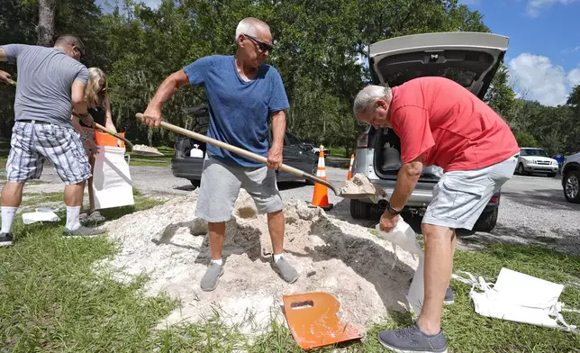 Roger Heim, right, and Terry Smith, second from right, both of Valrico, Fla., fill sand bags in preparation for a weekend storm at the Edward Medard Conservation Park in Plant City, Fla. (AP Photo/Chris O'Meara)