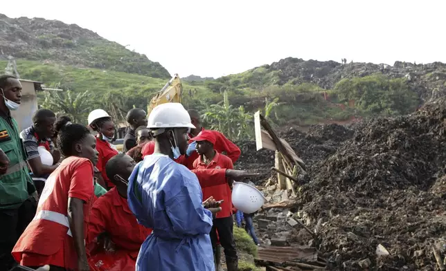 Onlookers watch as workers search for survivors at the site of a collapsed landfill in Kampala, Uganda, Sunday, Aug. 11, 2024. (AP Photo/Hajarah Nalwadda)