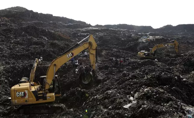 Onlookers watch as workers search for survivors at the site of a collapsed landfill in Kampala, Uganda, Sunday, Aug. 11, 2024. (AP Photo/Hajarah Nalwadda)