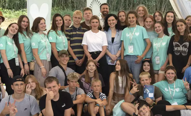 First lady Olena Zelenska, in white, poses for a photo during her visit to the rehabilitation camp "Loud Camp" for children affected by war, organized by the Voices of Children Charitable Foundation and financially supported by the Olena Zelenska Foundation in Uzhhorod, Ukraine, Tuesday, Aug. 27, 2024. (AP Photo/Efrem Lukatsky)