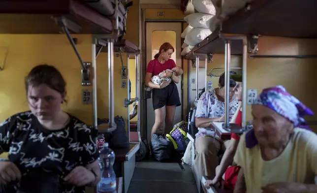 A girl calms her sister on an evacuation train in Pokrovsk, Donetsk region, Ukraine, Friday, Aug. 23, 2024. (AP Photo/Evgeniy Maloletka)