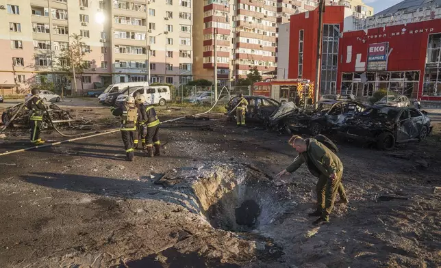 People look on crater after Russian airstrike on residential neighbourhood in Sumy, Ukraine, on Saturday, Aug. 17, 2024. (AP Photo/Evgeniy Maloletka)