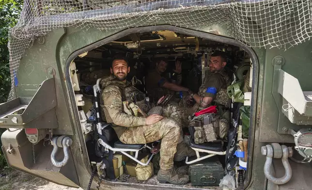 Ukrainian servicemen sit inside their APC after returning from Russian Kursk region, near Russian-Ukrainian border, Sumy region, Ukraine, Wednesday, Aug. 14, 2024. (AP Photo/Evgeniy Maloletka)