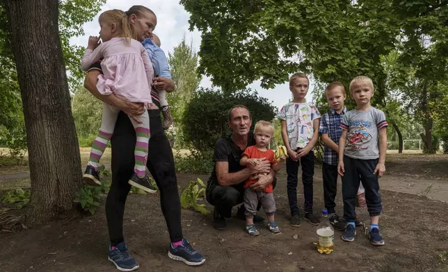 Iryna Belikova, 37, with her six children and husband, Ihor, wait for evacuation in Pokrovsk, Donetsk region, Ukraine, Friday, Aug. 23, 2024. (AP Photo/Evgeniy Maloletka)