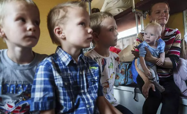 Iryna Belikova, 37, with her children, sit on an evacuation train in Pokrovsk, Donetsk region, Ukraine, Friday, Aug. 23, 2024.(AP Photo/Evgeniy Maloletka)