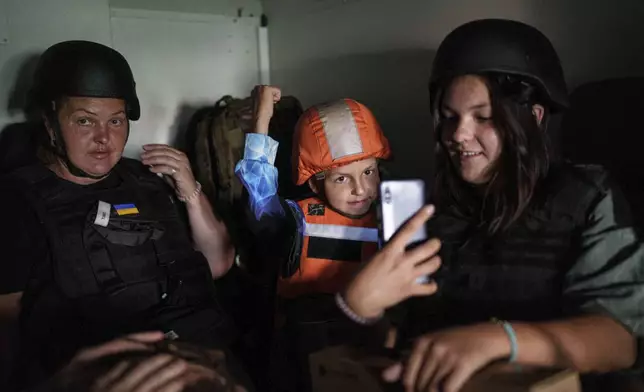 Maryna Scherbyna, left, and her children, 9 year old Bohdan Scherbyna and 14 year old Angelina Scherbyna ride inside an armoured van belonging to the emergency service Fenix team to be evacuated as local people are moved from Selidove to safe areas, in Pokrovsk, Donetsk region, Ukraine, on Tuesday, Aug. 20, 2024. (AP Photo/Evgeniy Maloletka)