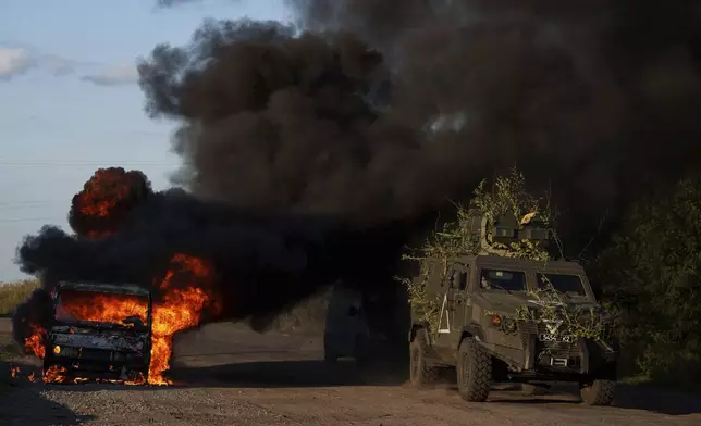 A Ukrainian armoured military vehicle travels past a burned car near the Russian-Ukrainian border, Sumy region, Ukraine, Wednesday, Aug. 14, 2024. (AP Photo/Evgeniy Maloletka)