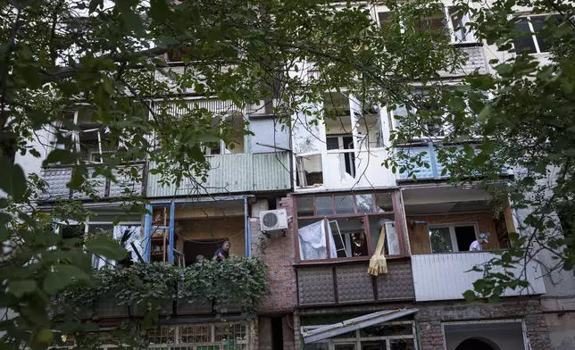 Local residents clear broken glass from their balconies after a Russian bombardment of a residential neighbourhood in Pokrovsk, Donetsk region, Ukraine, Tuesday Aug. 20, 2024. (AP Photo/Evgeniy Maloletka)