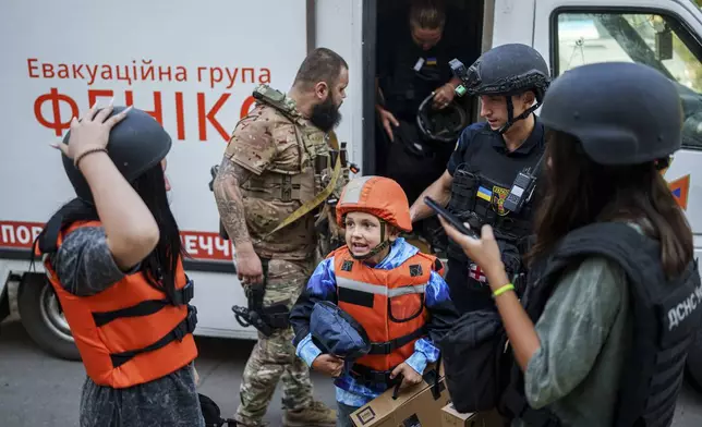 Bohdan Scherbyna, 9, with his mother Maryna Scherbyna, 45, and sister Angelina Scherbyna, 14, left, arrive in an armoured van belonging to the emergency service Fenix team during the evacuation of local people from Selidove to safe areas, in Pokrovsk, Donetsk region, Ukraine, on Tuesday, Aug. 20, 2024. (AP Photo/Evgeniy Maloletka)