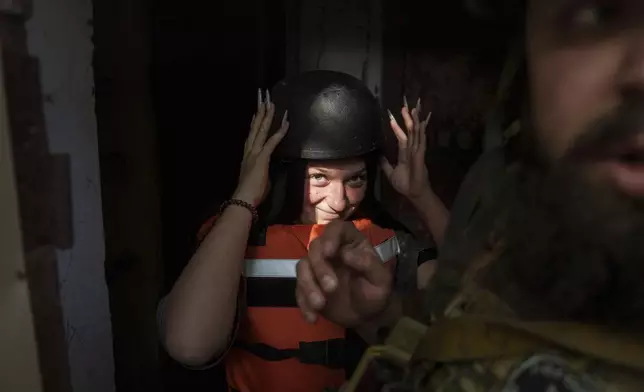 Sofia Zhuravleva, 14, wears a helmet as she is evacuated with her mother Maryna Scherbyna and 9 year old brother Bohdan Scherbyna, as local people are moved from Selidove to safe areas, in Pokrovsk, Donetsk region, Ukraine, on Tuesday, Aug. 20, 2024. (AP Photo/Evgeniy Maloletka)