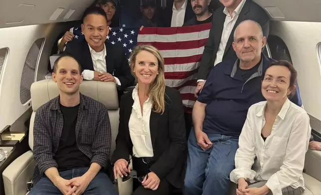 This image released by the White House shows Evan Gershkovich, left, Alsu Kurmasheva, right, and Paul Whelan, second from right, and others aboard a plane, Thursday, Aug. 1, 2024, following their release from Russian captivity. (White House via AP)