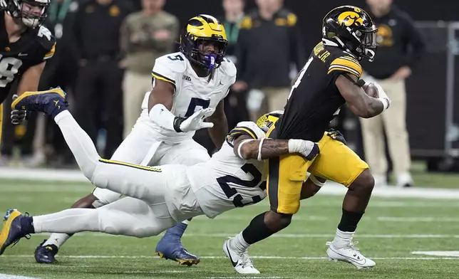 FILE - Iowa running back Leshon Williams (4) runs from Michigan linebacker Michael Barrett (23) and defensive end Josaiah Stewart (5) during the second half of the Big Ten championship NCAA college football game, Saturday, Dec. 2, 2023, in Indianapolis. (AP Photo/Darron Cummings, file)