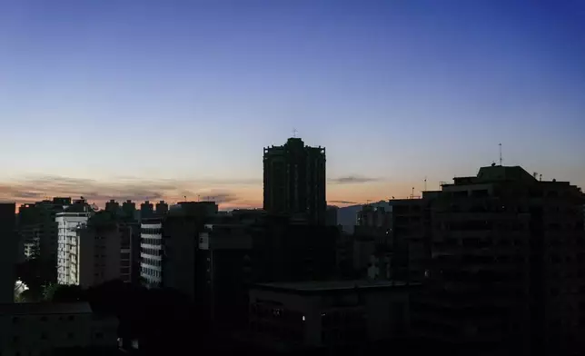 Buildings stand in darkness during a power outage in Caracas, Venezuela, at dawn on Friday, Aug. 30, 2024. (AP Photo/Ariana Cubillos)