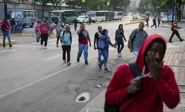 Pedestrians cross an avenue during a power outage in Caracas, Venezuela, early Friday, Aug. 30, 2024. (AP Photo/Ariana Cubillos)