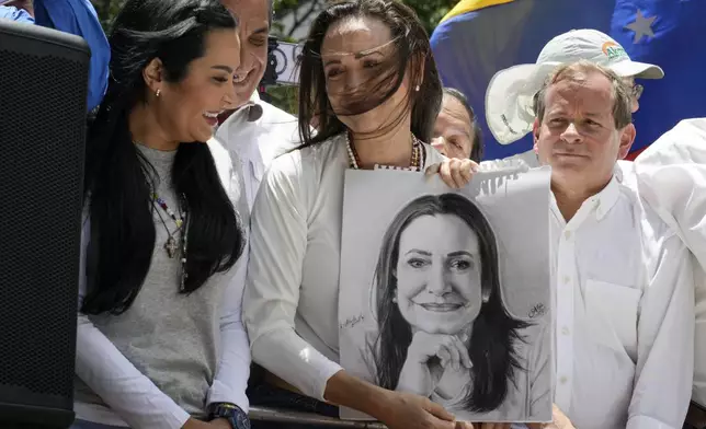 Opposition leader Maria Corina Machado holds a portrait of her, gifted to her by a supporter, during a protest against the reelection of President Nicolás Maduro one month after the disputed presidential vote which she says the opposition won by a landslide, in Caracas, Venezuela, Wednesday, Aug. 28, 2024. (AP Photo/Ariana Cubillos)