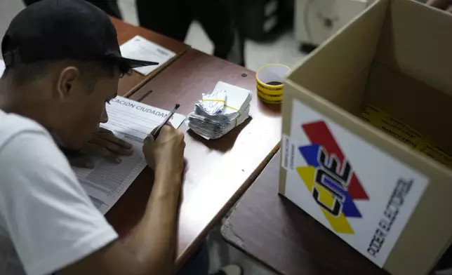 An election officials tallies votes after polls closed for the presidential election in Caracas, Venezuela, Sunday, July 28, 2024. (AP Photo/Matias Delacroix)