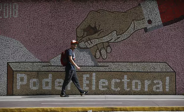 A man walks by a mural depicting a ballot box, outside the headquarters of the National Electoral Council in Caracas, Venezuela, Wednesday, July 31, 2024, three days after the country's disputed presidential election. (AP Photo/Cristian Hernandez)