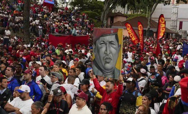 Government loyalists hold a poster of the late former President Hugo Chavez outside the presidential palace during a rally in support of President Nicolas Maduro's reelection one month after the presidential vote, in Caracas, Venezuela, Wednesday, Aug. 28, 2024. (AP Photo/Ariana Cubillos)