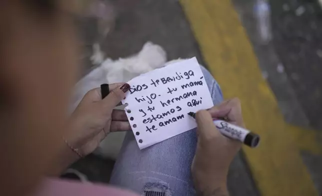 Franchesca Aponte writes a note to her brother outside the Boleita National Police detention center after he was arrested during opposition protests in recent days against the official results of the presidential election in Caracas, Venezuela, Thursday, Aug. 1, 2024. The note from Aponte and her mother reads in Spanish "God bless you son. Your mother and sister are here. We love you." (AP Photo/Matias Delacroix)