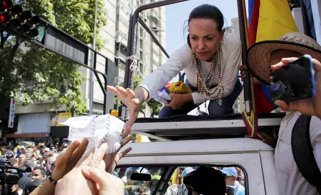 Opposition leader Maria Corina Machado reaches out to grab vote tally sheets during a rally to protest official results that declared President Nicolas Maduro the winner of the July presidential election, in Caracas, Venezuela, Saturday, Aug. 17, 2024. (AP Photo/Cristian Hernandez)