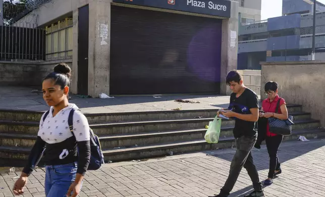 Pedestrians walk past a metro station that closed due to a blackout in Caracas, Venezuela, Friday, Aug. 30, 2024. (AP Photo/Ariana Cubillos)