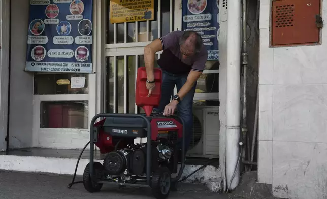 A business owner pours gas into a generator in Valencia, Venezuela, Friday, Aug. 30, 2024, during a blackout affecting most of the country. (AP Photo/Jacinto Olivares)