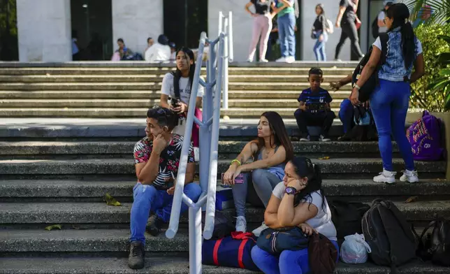 Workers sit outside their office building that closed due to a blackout in Caracas, Venezuela, Friday, Aug. 30, 2024. (AP Photo/Ariana Cubillos)