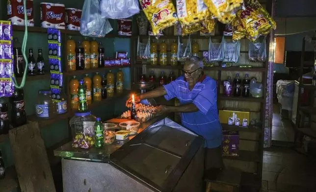 A man lights a candle in his shop during a blackout in Caracas, Venezuela, Friday, Aug. 30, 2024. (AP Photo/Ariana Cubillos)