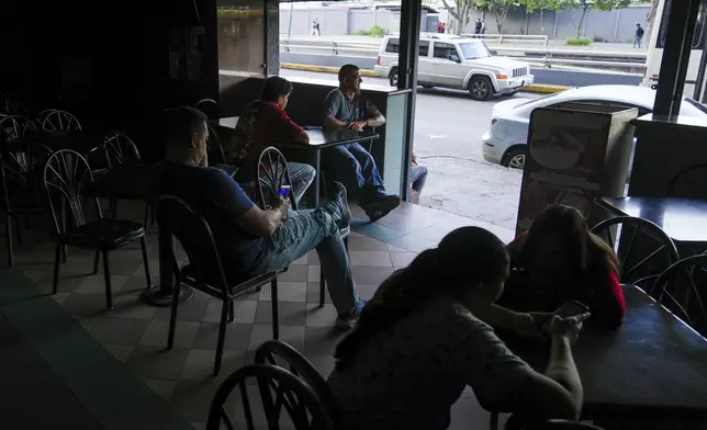 Costumers sit at a cafe during a blackout in Caracas, Venezuela, Friday, Aug. 30, 2024. (AP Photo/Ariana Cubillos)