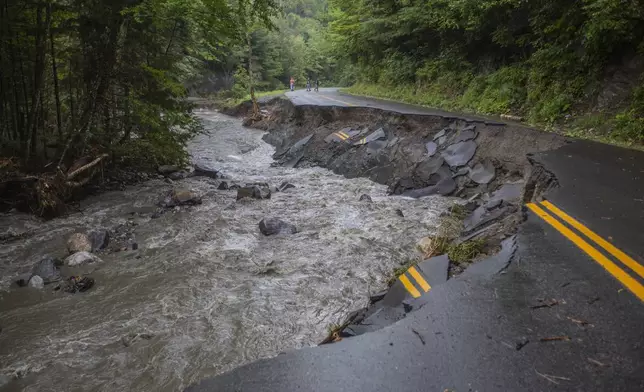 A river flows past a damaged road in the aftermath of flash floods in Lyndonville, Vermont, Wednesday, July 31, 2024. (AP Photo/Dmitry Belyakov)