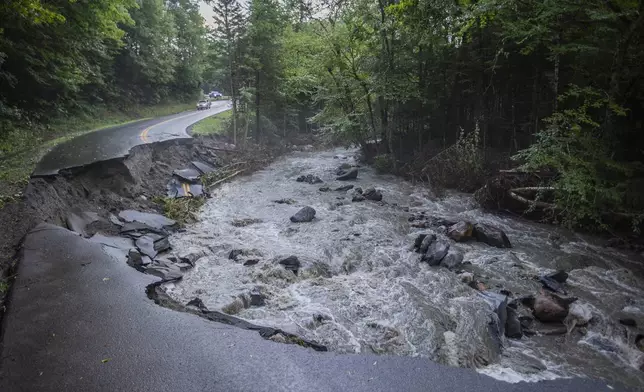 A river flows past a damaged road in the aftermath of flash floods in Lyndonville, Vt., Wednesday, July 31, 2024. (AP Photo/Dmitry Belyakov)