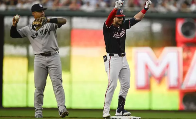 New York Yankees second baseman Gleyber Torres throws the ball as Washington Nationals' Dylan Crews celebrates his first major league hit at second base during the second inning of a baseball game, Tuesday, Aug. 27, 2024, in Washington. (AP Photo/John McDonnell)