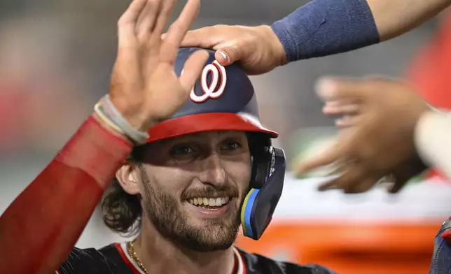 Washington Nationals' Dylan Crews is congratulated in the dugout by his teammates after scoring a run during the sixth inning of a baseball game against the New York Yankees, Tuesday, Aug. 27, 2024, in Washington. (AP Photo/John McDonnell)